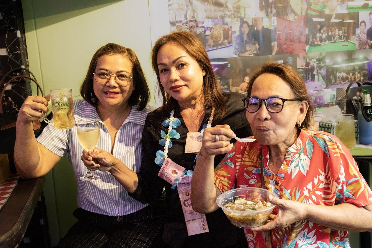 Three friends toasting with drinks and street food in hand