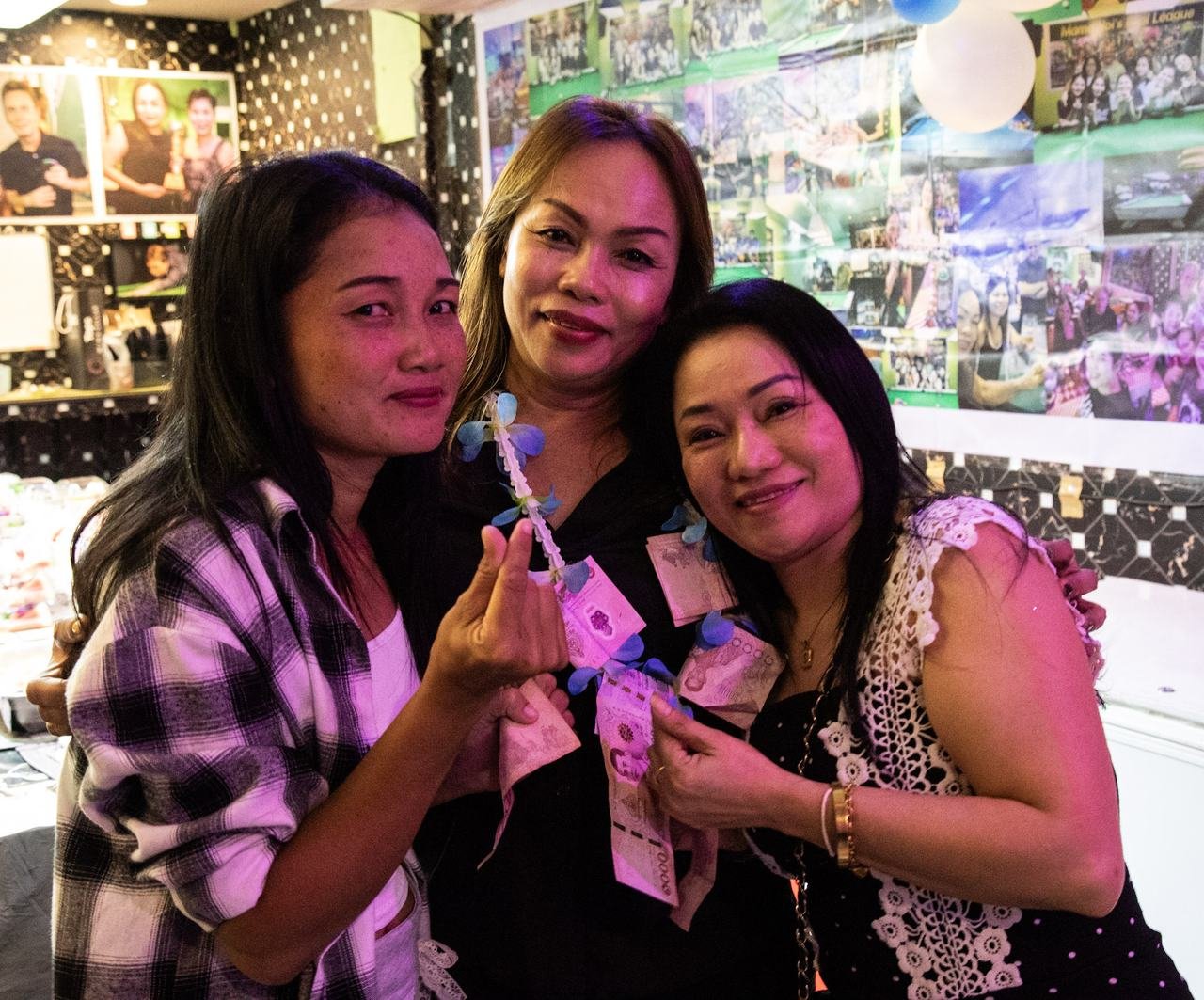 Three friends showing off the birthday money garland