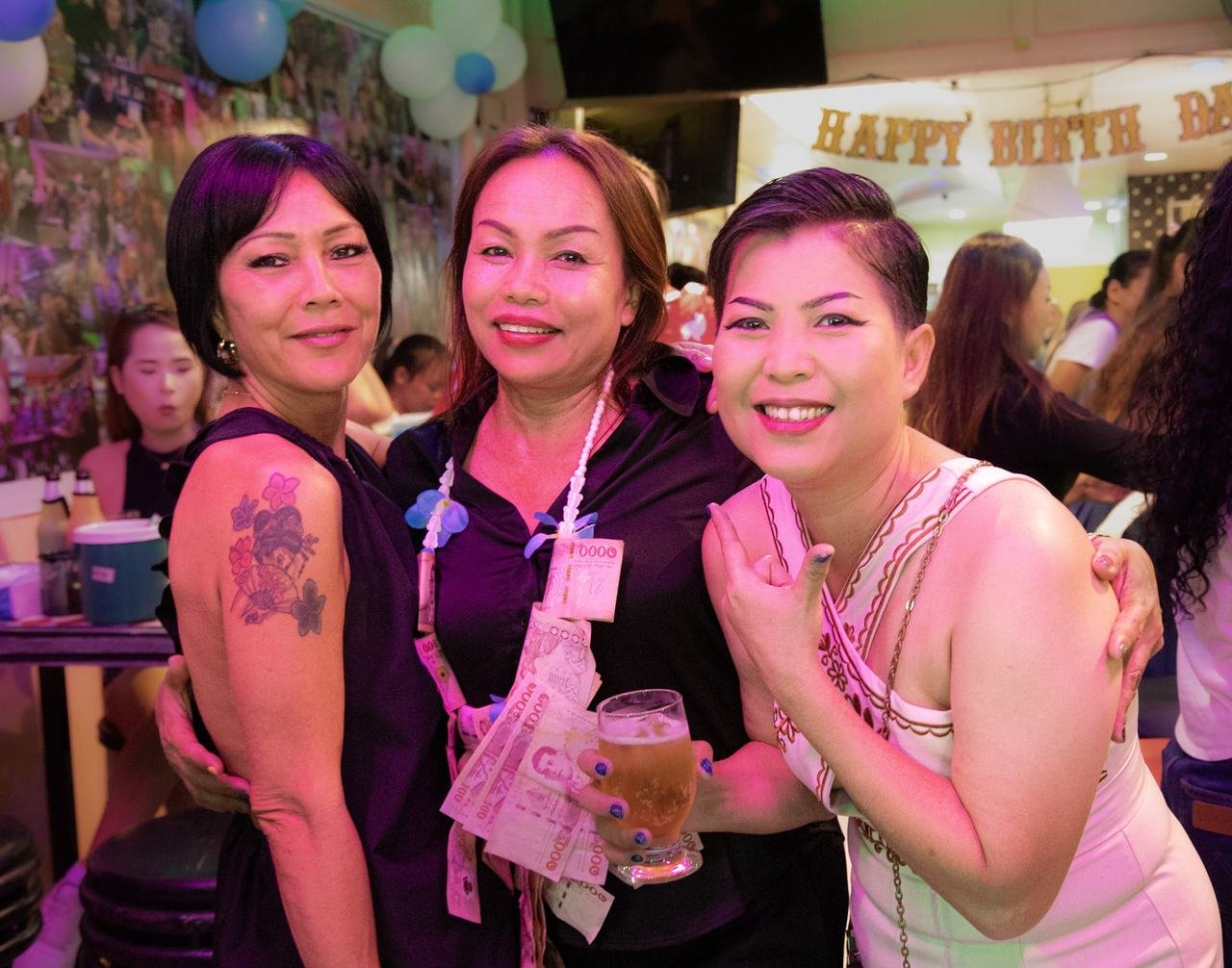 Three friends beaming together under the party lights