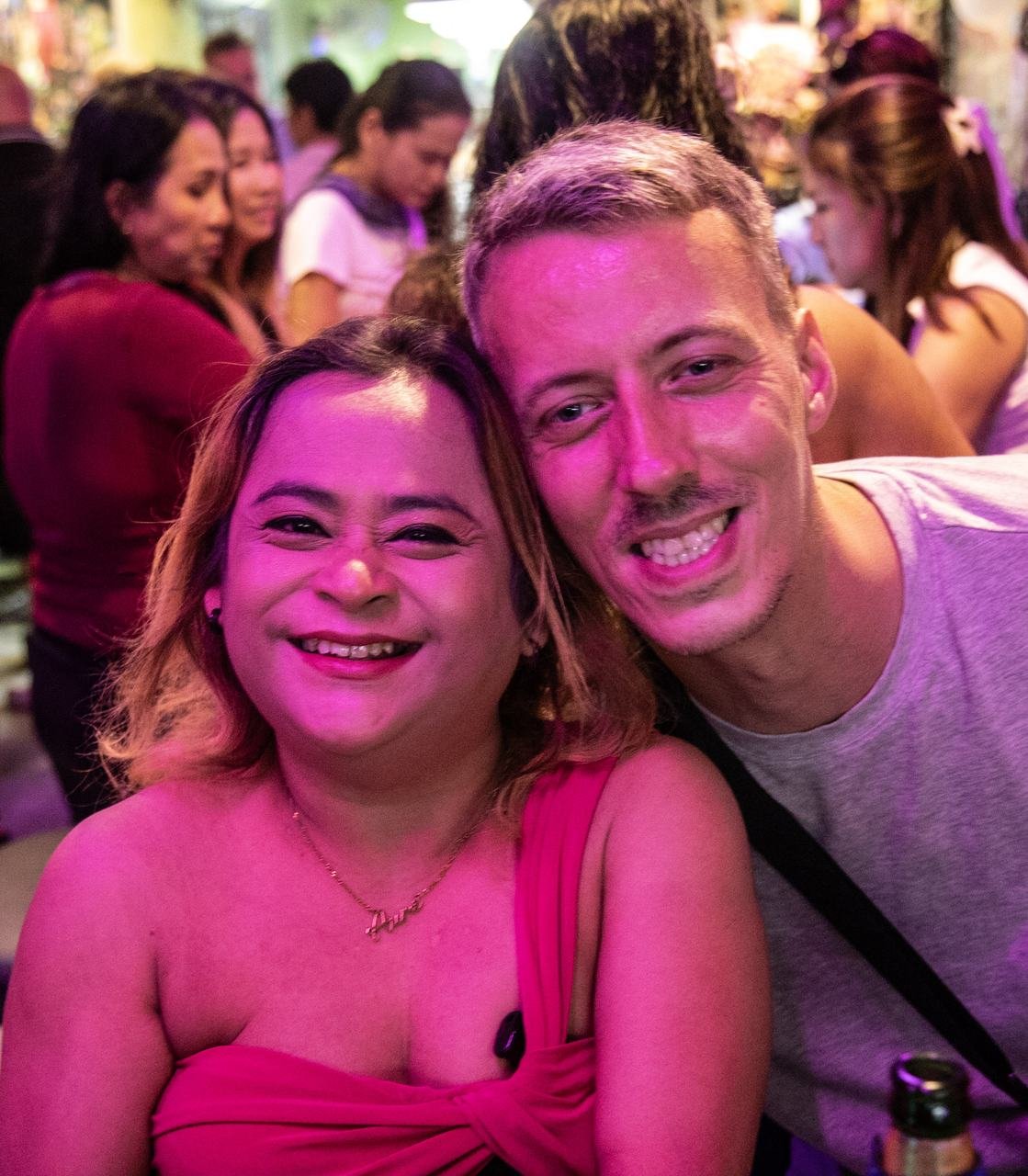 A close, cheerful moment shared under the pink lights